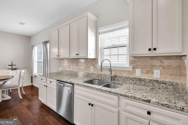 kitchen featuring a sink, light stone counters, backsplash, stainless steel dishwasher, and white cabinetry