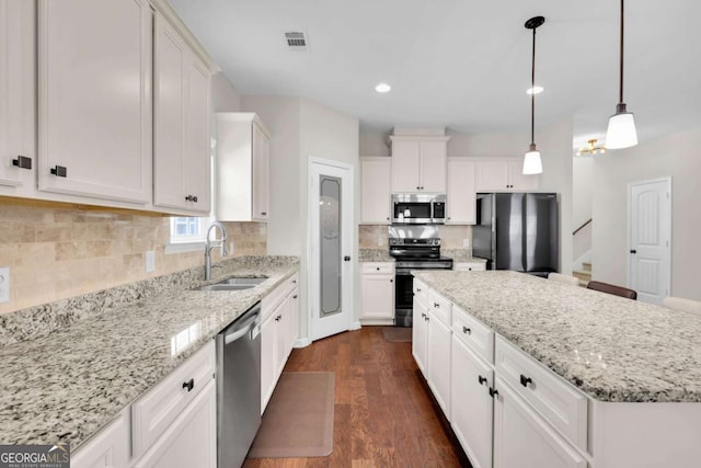 kitchen with a kitchen island, a sink, stainless steel appliances, dark wood-type flooring, and white cabinetry