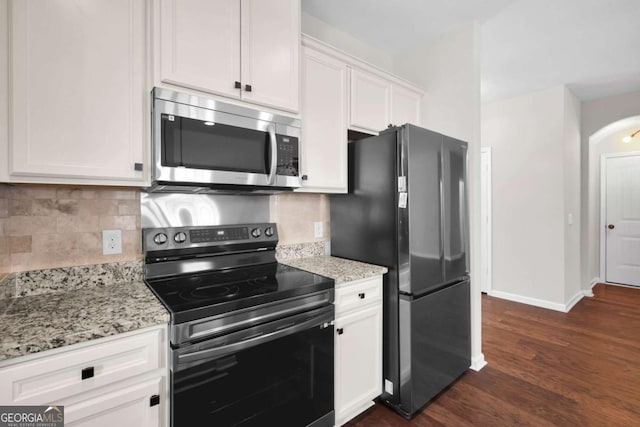 kitchen featuring dark wood-style flooring, arched walkways, appliances with stainless steel finishes, white cabinetry, and backsplash