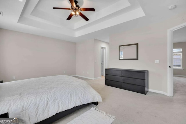 carpeted bedroom featuring a raised ceiling, visible vents, baseboards, and ceiling fan