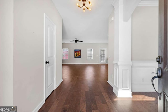 foyer entrance with dark wood finished floors, ceiling fan with notable chandelier, baseboards, and ornate columns