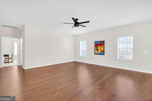 unfurnished room featuring dark wood-style floors, visible vents, baseboards, and a ceiling fan