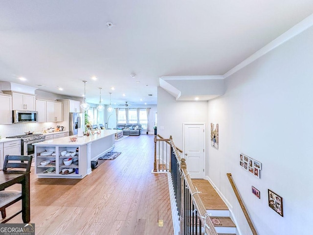 hall with recessed lighting, baseboards, an upstairs landing, and light wood-style floors