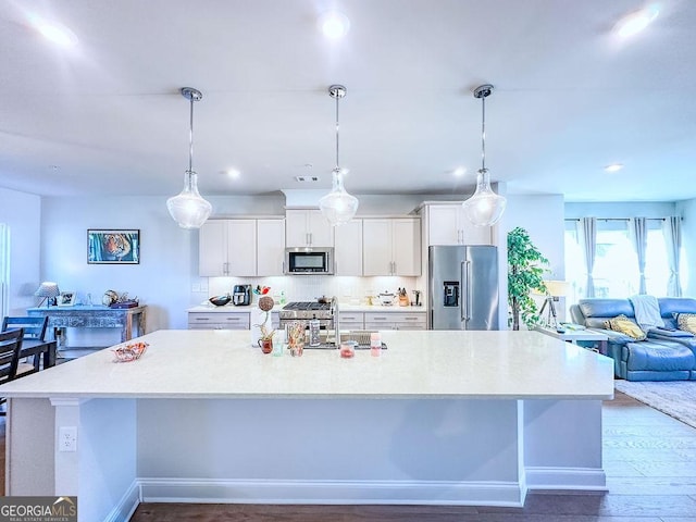 kitchen featuring white cabinetry, light countertops, a large island with sink, and stainless steel appliances