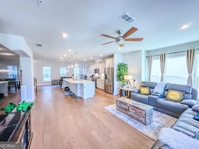 living room with light wood-type flooring, visible vents, ceiling fan, and recessed lighting