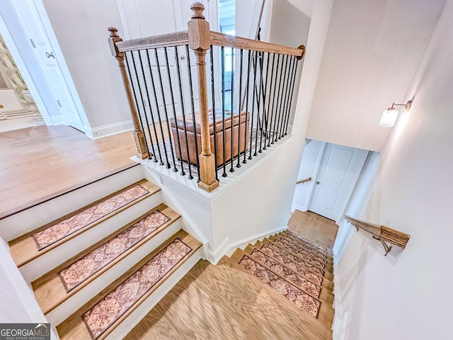 staircase with baseboards and wood finished floors