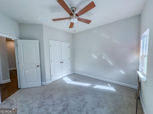 unfurnished bedroom with visible vents, ceiling fan, baseboards, carpet, and a closet