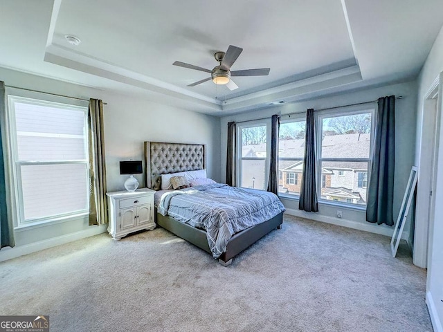 bedroom with a tray ceiling, baseboards, and light carpet