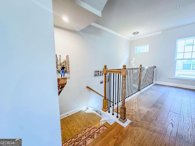 stairs featuring wood finished floors, baseboards, and ornamental molding