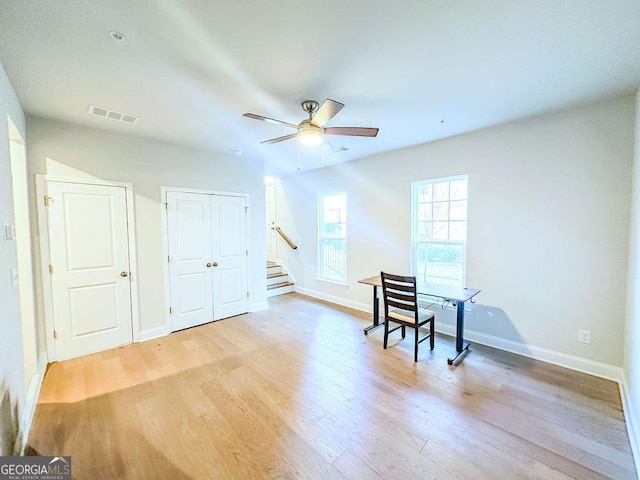 living area with visible vents, ceiling fan, baseboards, stairs, and light wood-style floors