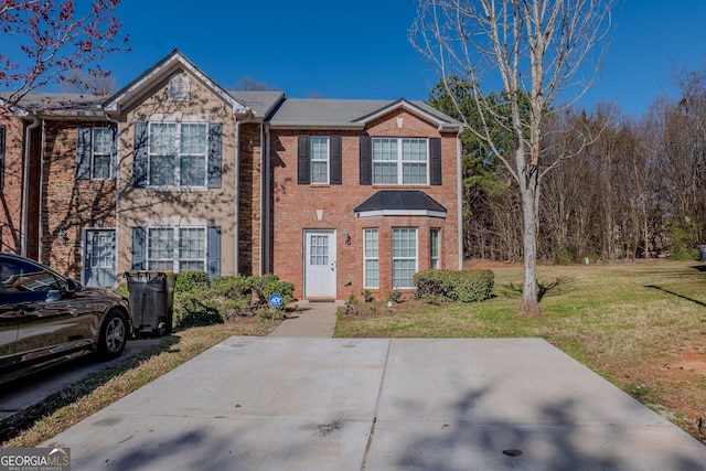 townhome / multi-family property with a front yard and brick siding