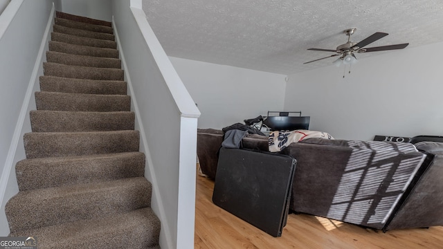 staircase featuring a ceiling fan, wood finished floors, and a textured ceiling