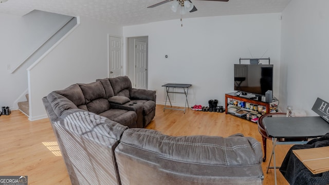 living room featuring a textured ceiling, stairway, wood finished floors, and ceiling fan