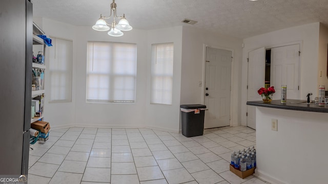 kitchen with visible vents, a notable chandelier, a textured ceiling, dark countertops, and light tile patterned floors