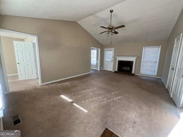 unfurnished living room with visible vents, ceiling fan, vaulted ceiling, carpet flooring, and a fireplace