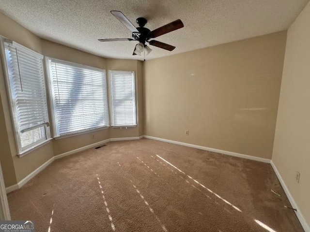 unfurnished room featuring visible vents, a textured ceiling, baseboards, and a ceiling fan