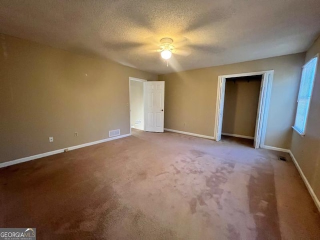 unfurnished bedroom featuring baseboards, a textured ceiling, carpet floors, and a ceiling fan