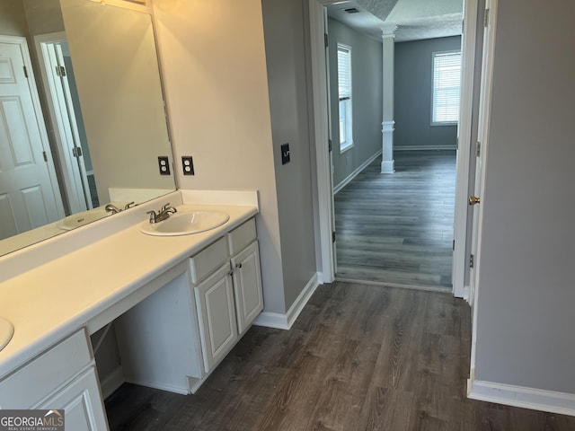 bathroom featuring vanity, decorative columns, wood finished floors, and baseboards