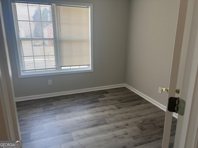 empty room with baseboards and dark wood-type flooring