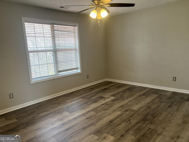 empty room with a ceiling fan, dark wood-style floors, a healthy amount of sunlight, and baseboards