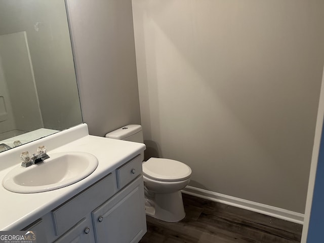 bathroom with baseboards, toilet, wood finished floors, and vanity