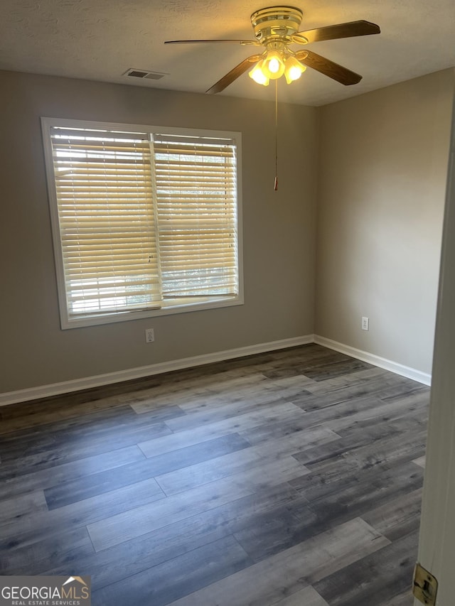 empty room featuring dark wood finished floors, visible vents, plenty of natural light, and ceiling fan