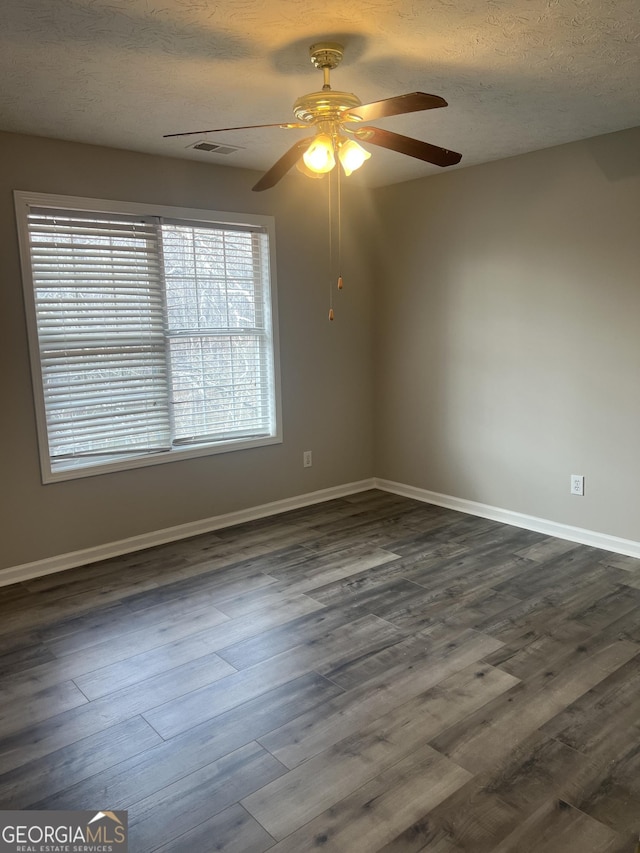 unfurnished room with visible vents, dark wood-type flooring, baseboards, ceiling fan, and a textured ceiling