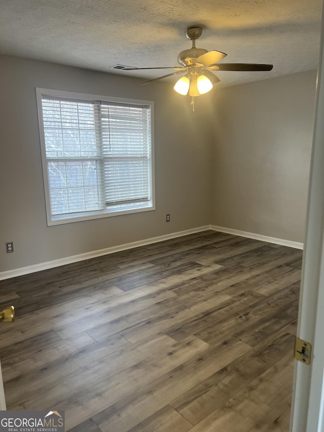 empty room featuring dark wood finished floors, baseboards, a textured ceiling, and a ceiling fan