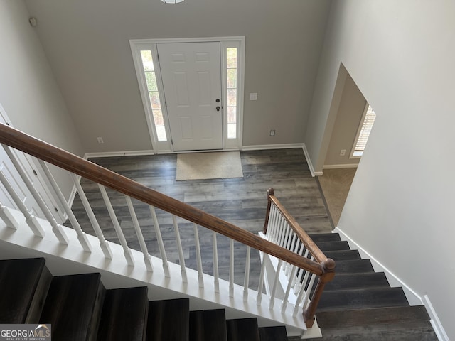 foyer featuring baseboards, wood finished floors, and stairs