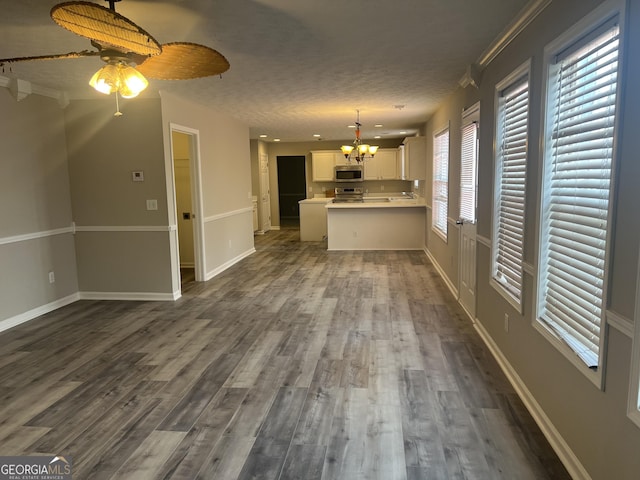 unfurnished living room featuring dark wood finished floors, ceiling fan with notable chandelier, baseboards, and a textured ceiling