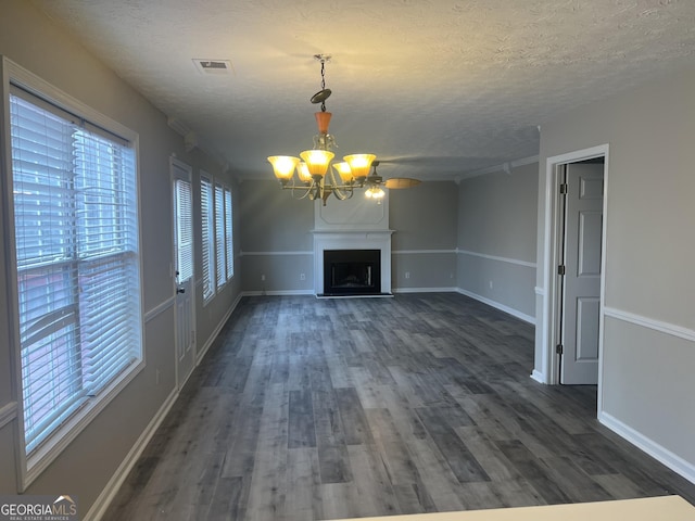 unfurnished living room with dark wood-type flooring, a notable chandelier, visible vents, and a textured ceiling