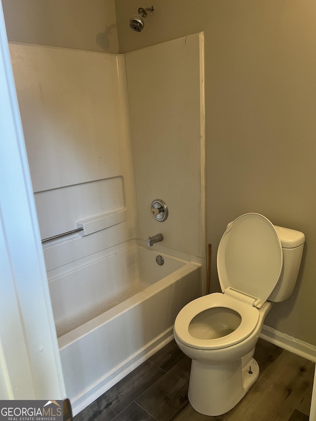 full bathroom featuring baseboards, toilet, wood finished floors, and bathing tub / shower combination