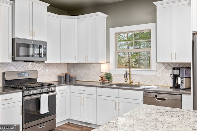 kitchen with a sink, stainless steel appliances, tasteful backsplash, and white cabinets