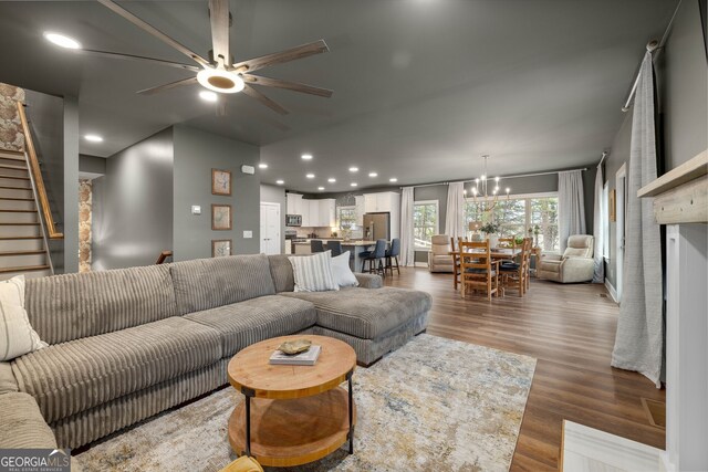 living area with recessed lighting, wood finished floors, stairs, and ceiling fan with notable chandelier