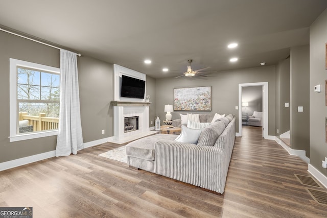 living area featuring a fireplace, recessed lighting, wood finished floors, and a ceiling fan