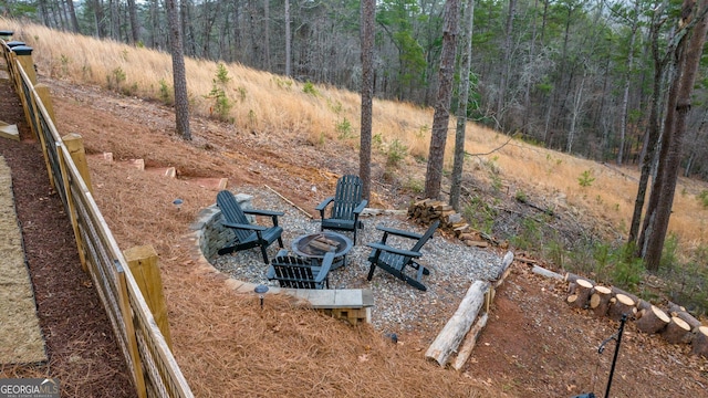 view of yard featuring a view of trees and an outdoor fire pit