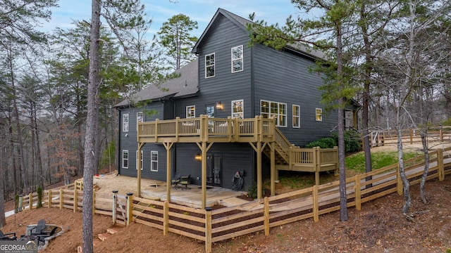 rear view of property featuring roof with shingles, a deck, stairs, and fence