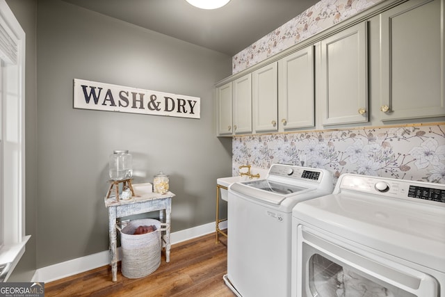 clothes washing area featuring wood finished floors, baseboards, washing machine and clothes dryer, cabinet space, and a sink