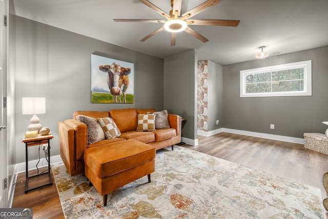 living area with a ceiling fan, wood finished floors, and baseboards