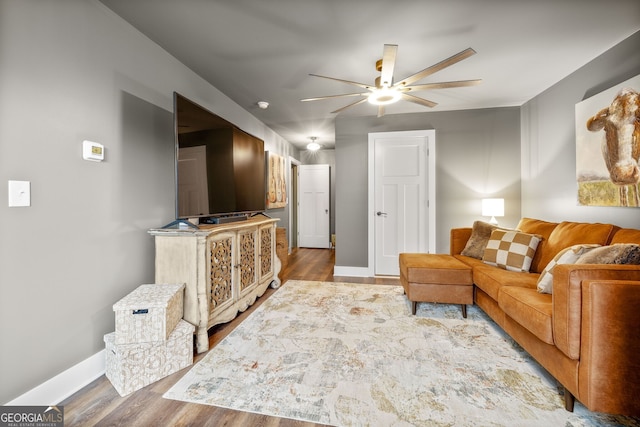 living area featuring baseboards, wood finished floors, and ceiling fan