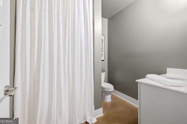 bathroom with toilet, baseboards, and concrete floors