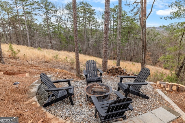 view of yard with an outdoor fire pit and a forest view