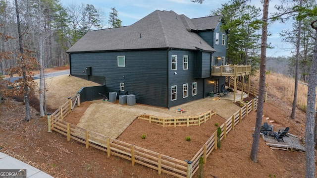 back of house with central air condition unit and a shingled roof