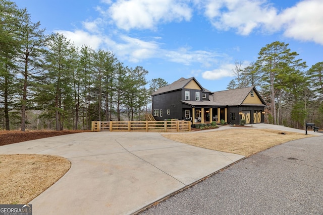 view of front of home featuring a porch, concrete driveway, a garage, and fence