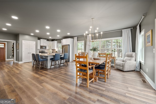 dining room with wood finished floors, visible vents, and a chandelier