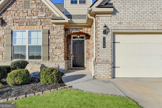 doorway to property featuring stone siding, concrete driveway, a shingled roof, and a garage