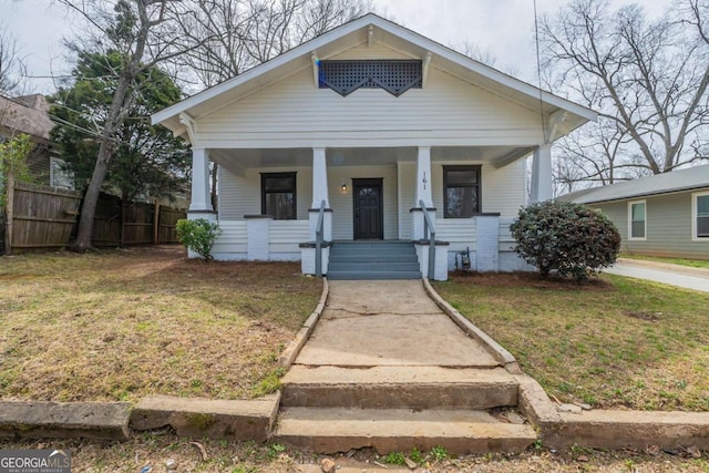 bungalow-style house with covered porch, a front yard, and fence