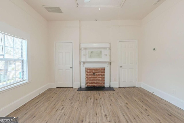 unfurnished living room with visible vents, attic access, baseboards, and wood finished floors