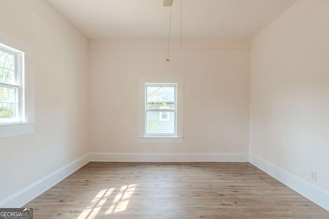 spare room featuring plenty of natural light, wood finished floors, and baseboards