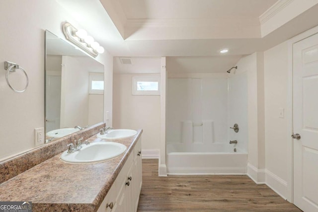 bathroom featuring wood finished floors, crown molding, shower / bathing tub combination, and a sink